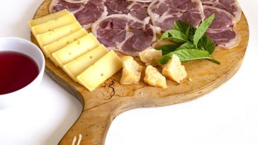 Abbinamenti di formaggi e salumi su un tagliere rustico
