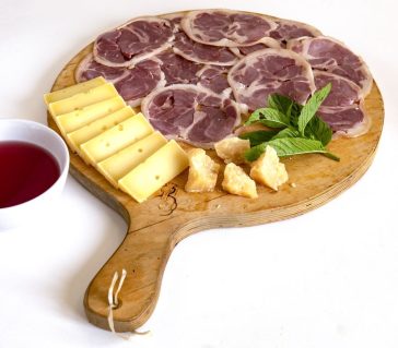 Abbinamenti di formaggi e salumi su un tagliere rustico